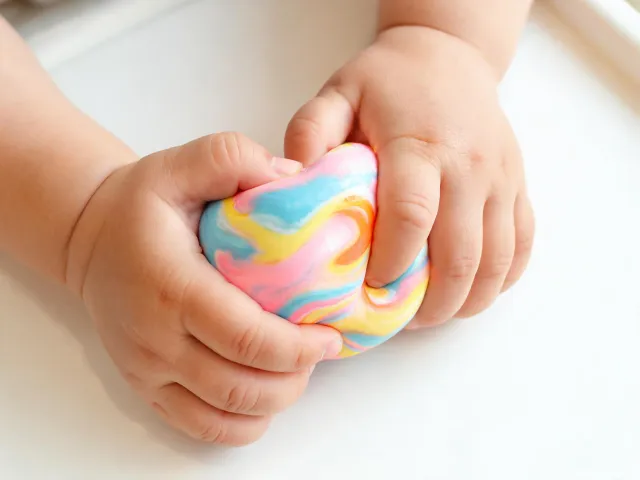 Toddler squeezing a colorful squishy toy